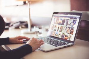 Un ordinateur portable est posé sur un bureau. Une femme est assise devant et travaille.