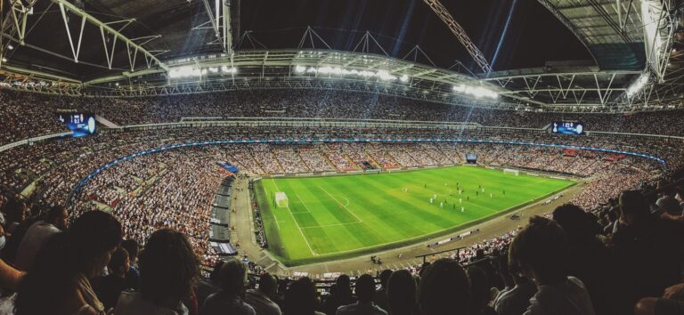 Muestra un estadio de fútbol lleno bajo los focos