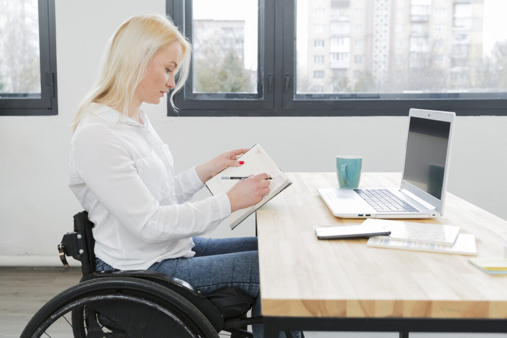 Frau im Rollstuhl die am Laptop arbeitet