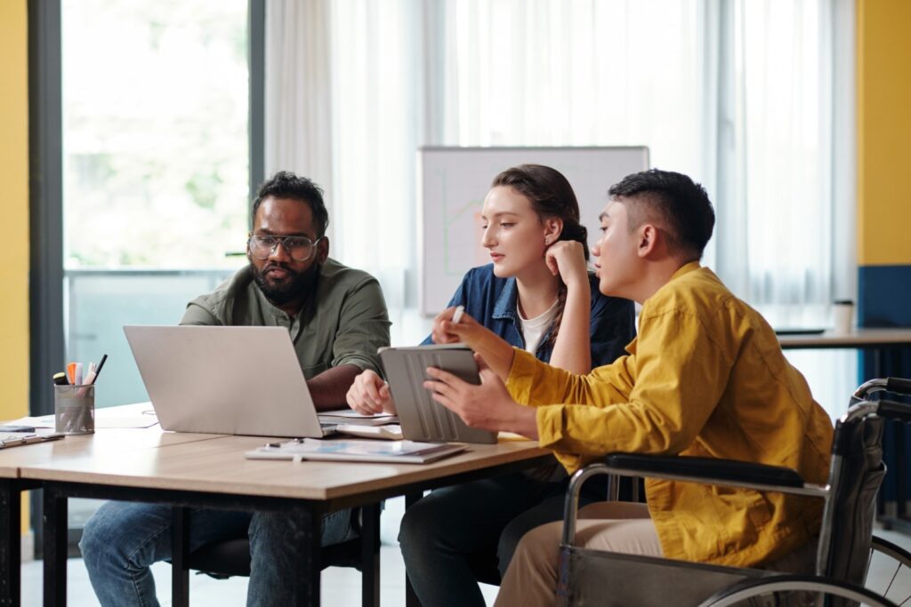 Drei Menschen sitzen gemeinsam vor einem Laptop