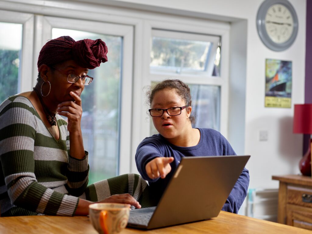 2 people sitting in front of a laptop