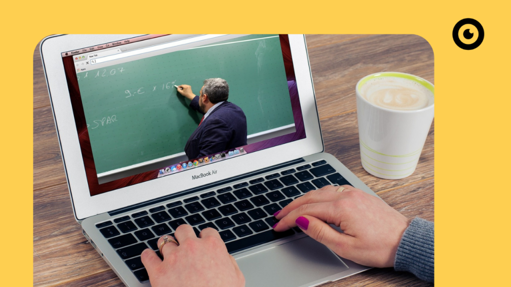 Video on a laptop of a teacher standing in front of a blackboard.