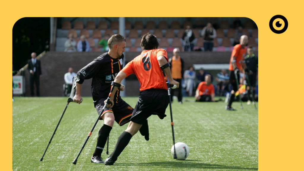 Mensch mit Krücken beim Fußball spielen.